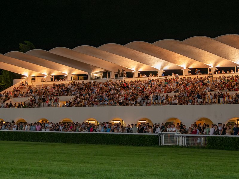 Tribuna del hipódromo iluminada y llena de público por la noche